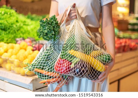 Zero waste concept with copy space. Woman holding cotton shopper and reusable mesh shopping bags with vegetables, products. Eco friendly mesh shopper. Zero waste, plastic free concept