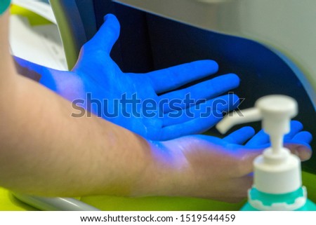 Someone has disinfected his hands and controls the result under uv light. Concept: cleanliness and protection against germs Royalty-Free Stock Photo #1519544459
