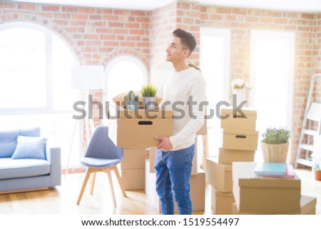 Young man smiling holdig cardboard box, happy moving to a new house