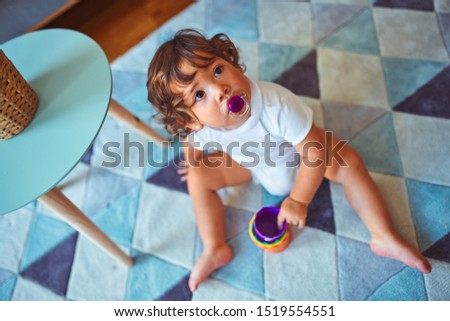 Beautiful toddler child girl using pacifier playing with toys on the carpet