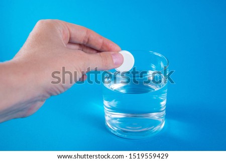 A hand holding effervescent soluble calcium tablet or vitamin C is placed in a glass of water. Health.The concept of a healthy lifestyle, prevention of vitamin deficiency. Isolated on white background