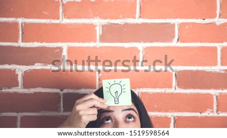 bulb on paper on woman head on brick wall background