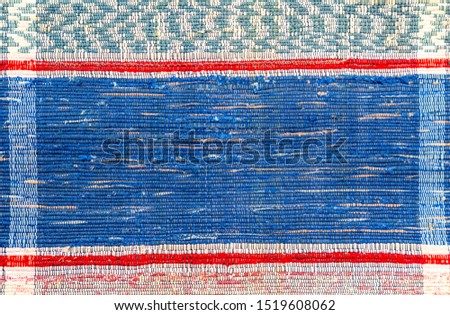 Old handmade doormat from strips of cloth as background. Texture of a homespun rug from different fabrics