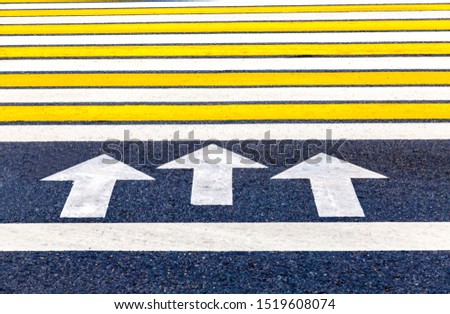Pedestrian crossing with arrows, white and yellow stripes close up