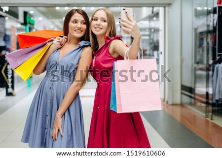 Two pretty girls make selfies in the mall after shopping
