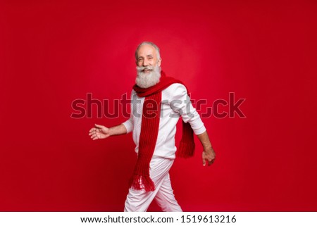 Portrait of attractive pensioner walking smiling wearing white jumper pants trousers isolated over red background