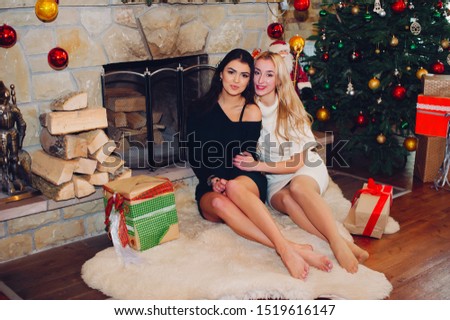 Two beautiful girls in a decorated room. Women near Christmas tree. Ladies in a sweaters