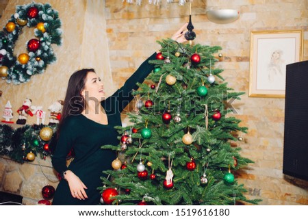 Beautiful girl in a decorated room. Woman near Christmas tree. Lady in a sweaters