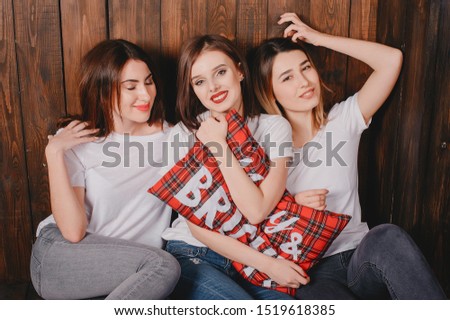 Three beautiful girls in a photo studio. Ladies in a white t-shirts