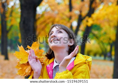 teen girl posing with autumn leaves in city park, outdoor portrait