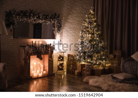 Stylish interior with beautiful Christmas tree and artificial fireplace at night