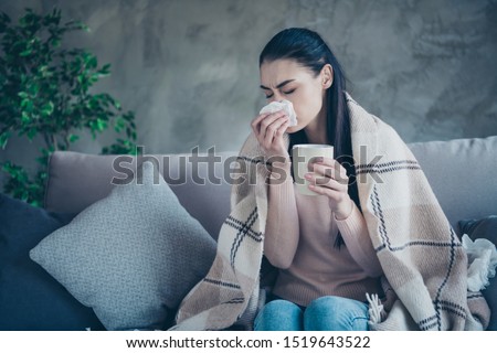 Photo of suffering lady with cup and napkin caught cold drinking medicine from flu covered with blanket wearing pullover and jeans sitting sofa
