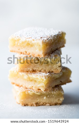 Front facing view of a stack of four lemon squares with powdered sprinkled on top.
