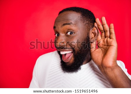 Close up photo of interested curious dark skin man hold hand near ears listen confidential promo about x-mas wonder feel impressed wear style white sweater isolated over red color background
