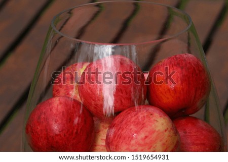 Beautiful image of red apples in a glass vase on a wooden rustic table close-up.Glittering highlights on the glass