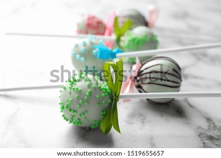 Different tasty cake pops on white marble background