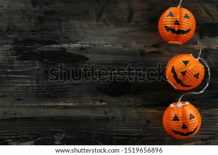 Orange pumpkin shaped lamps, creepy and funny Jack o Lantern decor lights on dark background. All hallows night. Copy space, close up, top view. Halloween party decoration. Trick or treat concept.