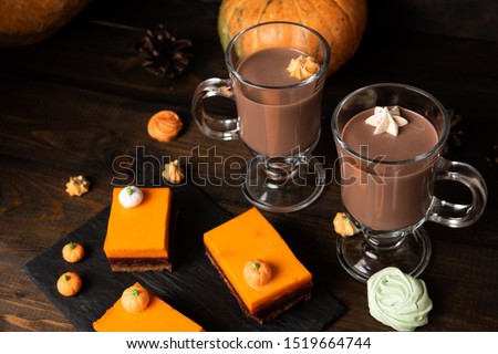 A slice of delicious homemade pumpkin pie and glasses of hot chocolate on dark wooden background