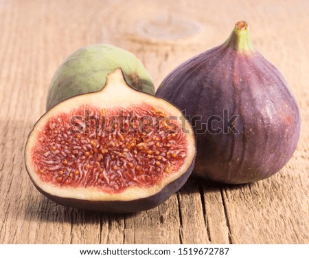 Fresh figs, half and whole on wooden plank, close up. Food photo