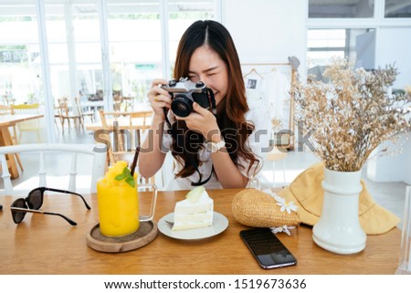 A woman take a photo of her dessert and drink that she order at the cafe.