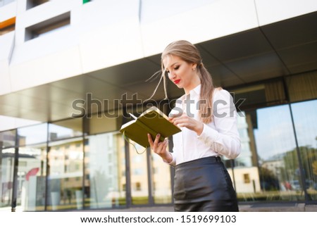 Young student looks in her diary. Stylish schoolgirl with a book in her hands is preparing for lessons