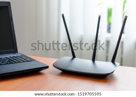 wireless wifi router and laptop at wooden table indoors. window behind. wireless connection concept Royalty-Free Stock Photo #1519705595
