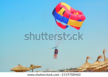 Two women parasailing fly over the beach