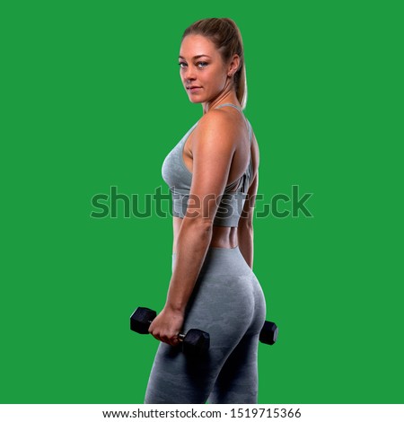 Confident athlete woman looking at camera, strong physique, toned arms, muscular fit body on green screen