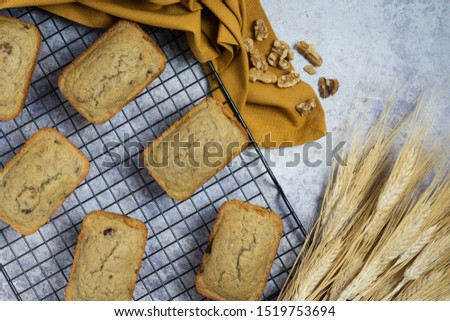 mini muffin loaves on a black wire baking rack with a gold napkin, walnuts and wheat sheaves on a marble countertop