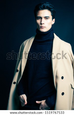 cool real young man in coat on black background posing, lifestyle people concept