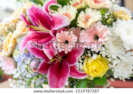 A beautiful arrangement of fresh flowers asters, baby's breath, chrysanthemums, roses and lily flowers as a foreground.