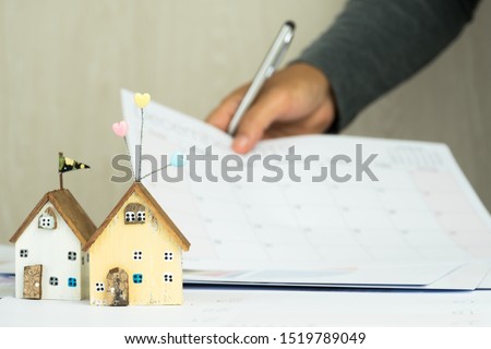 Business people signature in documents graph checking calendar document in property investment project on desk office. Report selling in mortgage marketing in real estate concept. Two house focus