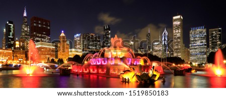 Chicago skyline illuminated at dusk with colorful Buckingham fountain on the foreground