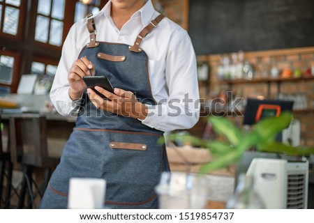 Waiter using touch pad or smart phone to send customer order in the restaurant. Modern wireless technology for retaurant or coffee shop. Royalty-Free Stock Photo #1519854737