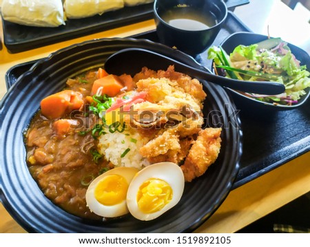 Japanese food - Fried Chicken Karaage Don served with white rice, curry, two half boiled eggs, salad and miso soup on a table. Halal food in Malaysia restaurant.