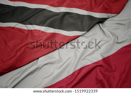 waving colorful flag of poland and national flag of trinidad and tobago. macro