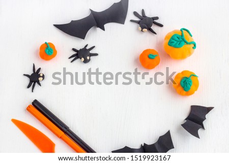 Halloween decoration from plasticine: pumpkins and spiders on a white wooden background. Top view, copy space. Concept of preparation to halloween in the kindergarten.