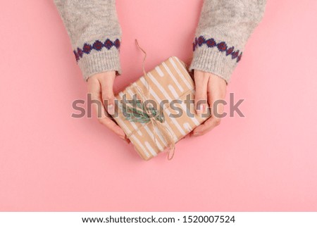 Top view of woman hands holding gift box on pink background