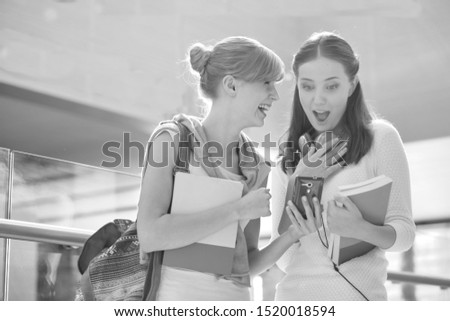 Black and white photo of Young female student showing mobile phone to her classmate