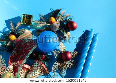 Blue candle and red, gold Christmas decorations on blue background