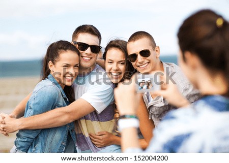 summer holidays and technology concept - group of teenagers taking photo outside
