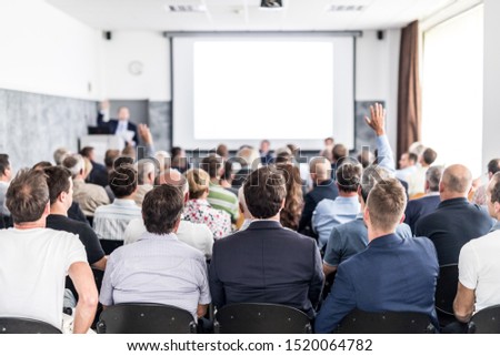 President of the management board presents past year company performance at annual general meeting of shareholders. Businesspeople with raised hands voting on resolutions of assembly. Royalty-Free Stock Photo #1520064782
