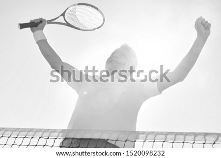 Black and white photo of happy senior man winning tennis match