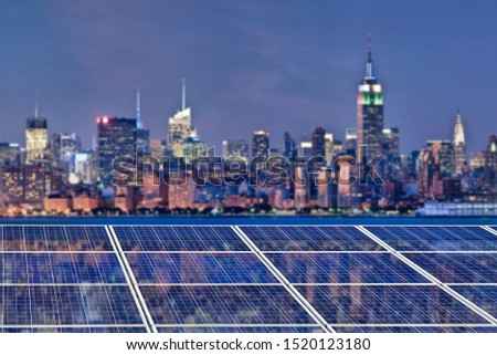 Blue solar cell panels, New York skyline illuminated at night in the background