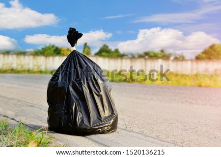 black garbage bag is and waste food placed next to the on the road floor on blue sky background