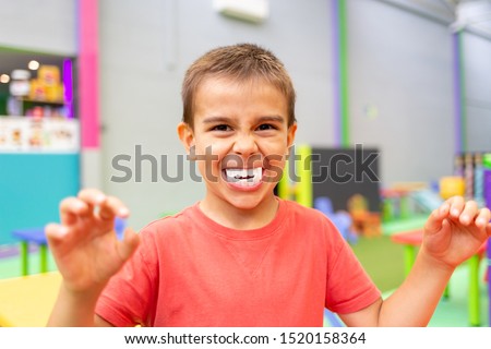little boy with big plastic vampire teeth toy for halloween