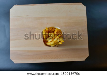 French fries on a wooden board isolated on black