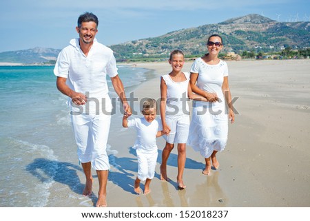 Photo of happy family running down the beach on summer