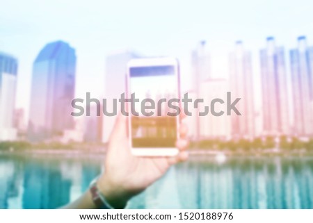 Soft focus blurred hand of a man Photographing view of a building with mobile phone