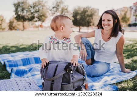 young mother playing with baby girl outdoors in a park, happy family concept. love mother daughter